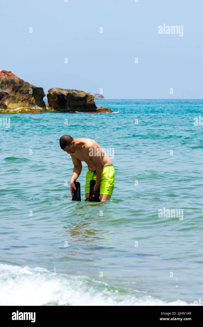 Junger Araber, der in der Nähe des Strandes im Mittelmeer steht. Konzept für Sommerferien. Stockfoto