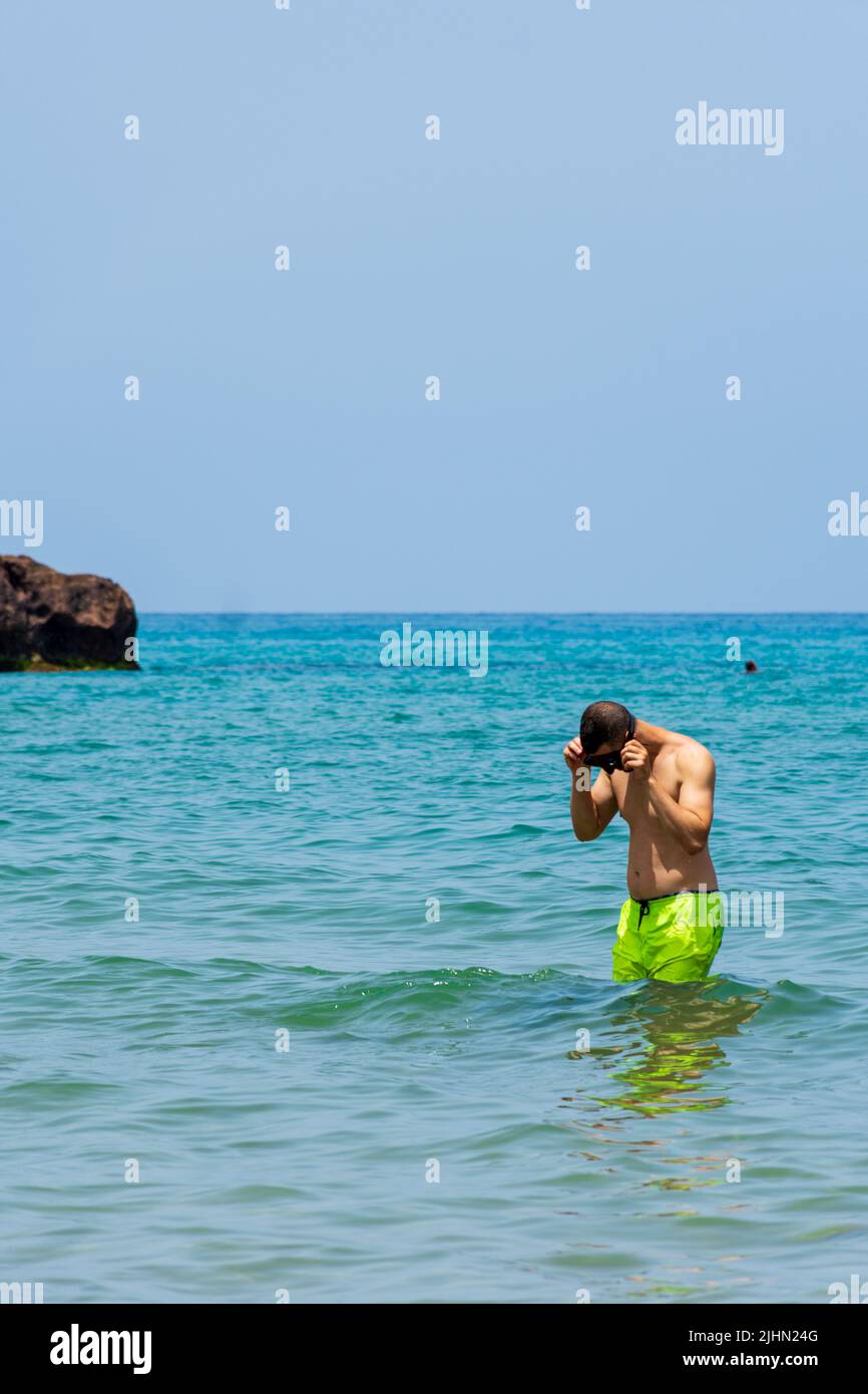 Junger Araber, der in der Nähe des Strandes im Mittelmeer steht. Konzept für Sommerferien. Stockfoto