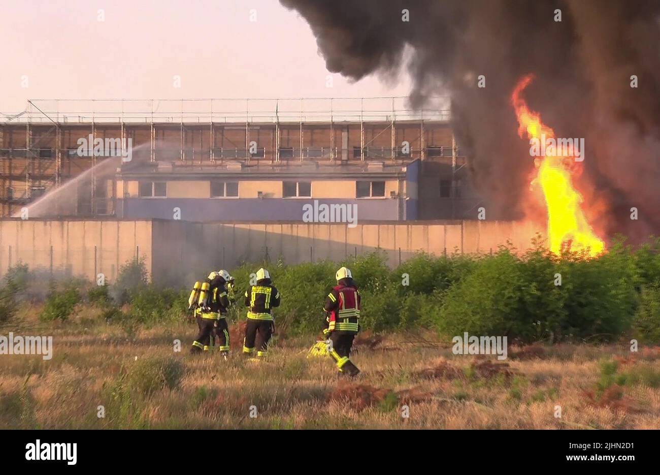 Premnitz, Deutschland. 19.. Juli 2022. Löschkräfte löschen einen Brand in einem Chemiewerk. In einem Lager eines Chemiefaserherstellers im Bezirk Havelland brach am Dienstagabend ein weithin sichtbares Feuer aus. Es gab eine starke Rauchentwicklung, sagte ein Feuerwehrsprecher am Abend, in der Halle wahrscheinlich Kunststoff und Holz gelagert. Die Halle gehört einem Polyesterfaserhersteller. Quelle: Cevin Dettlaff/dpa-Zentralbild/dpa/Alamy Live News Stockfoto