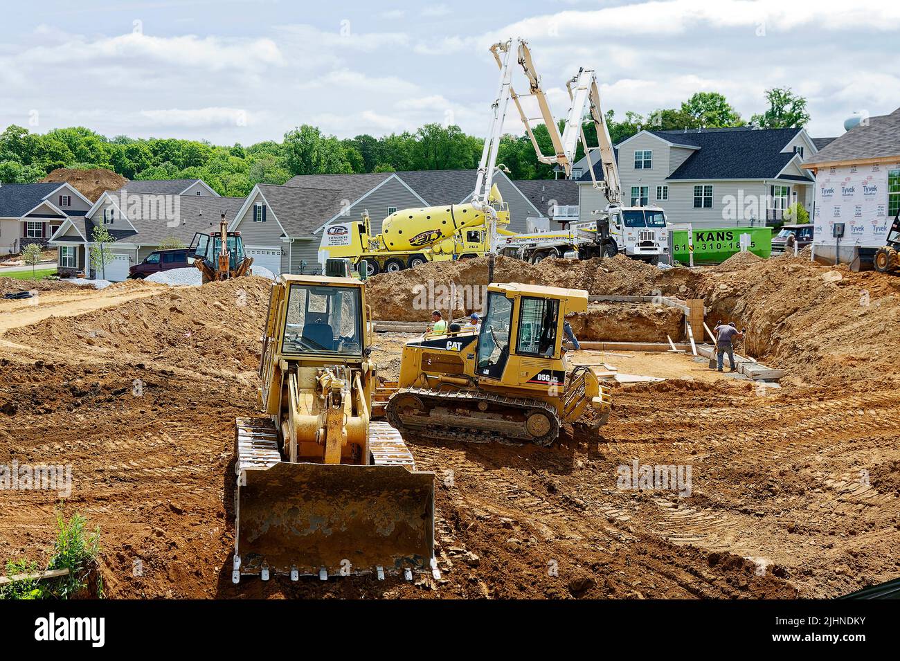 Neubau, schwere Ausrüstung, bewegliche Schmutzwälle; Grading, Fundament, Fertig gestellte Häuser, Industrie, Männer arbeiten, Unternehmen, Gemeinde, Echte es Stockfoto