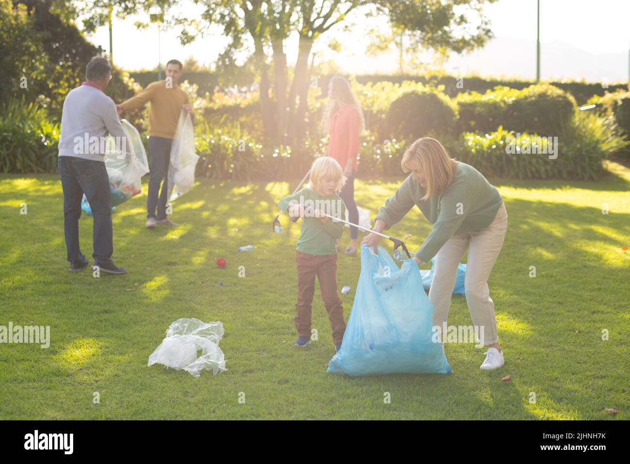 Bild einer glücklichen, mehrgenerationenigen Kaukasusfamilie, die Abfälle im Garten sammelt Stockfoto