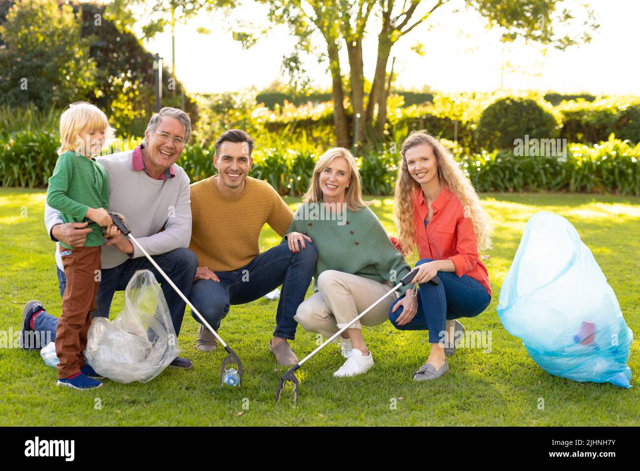 Bild einer glücklichen, mehrgenerationenigen Kaukasusfamilie, die Abfälle im Garten sammelt Stockfoto