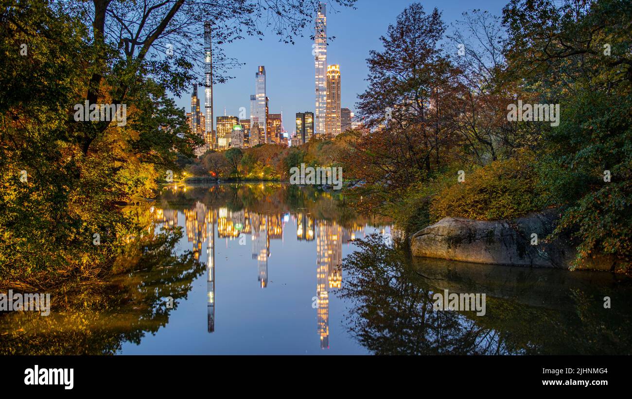 Herbstlaub in Dawn im Central Park mit See und Skyline Stockfoto