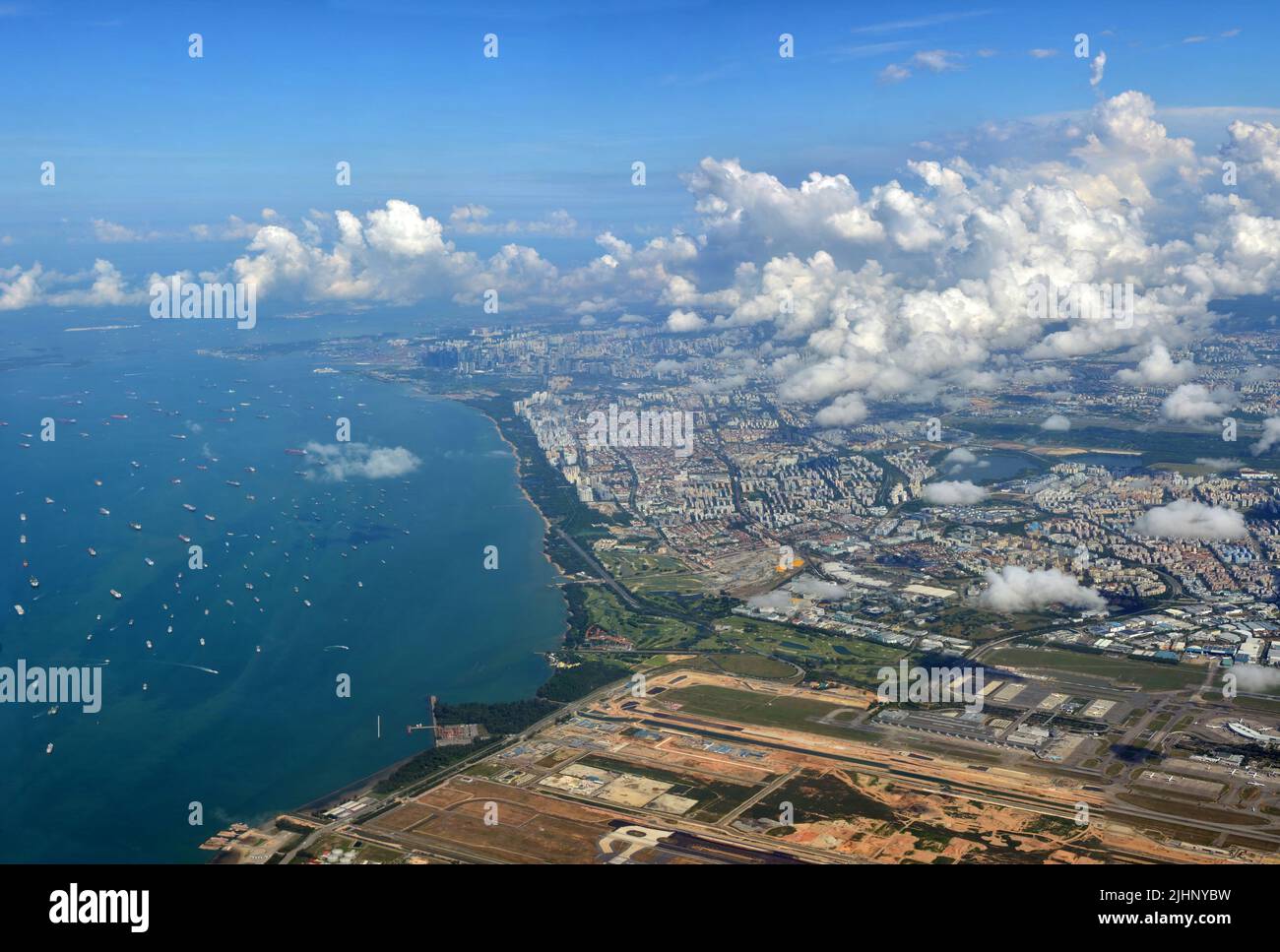Ankunft am Changi Airport, Singapur, mit der Start- und Landebahn im Vordergrund und dem Hafen im Hintergrund. Stockfoto