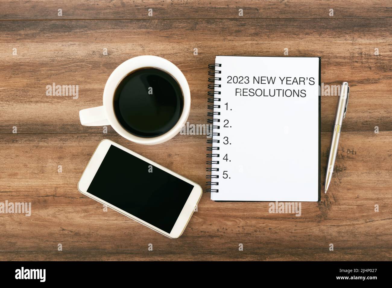 2023 Neujahrsauflösung Text auf Notizblock mit Smartphone, Stift und Tasse Kaffee Stockfoto