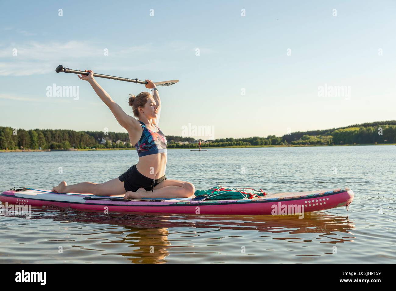 Sport Frau Yogini Skorpion Pose Praxis Yoga-Übung auf supboard auf dem Meer in entspannenden Tag, Yoga ist Meditation und gesunde Sport concept.Yoga auf Stockfoto