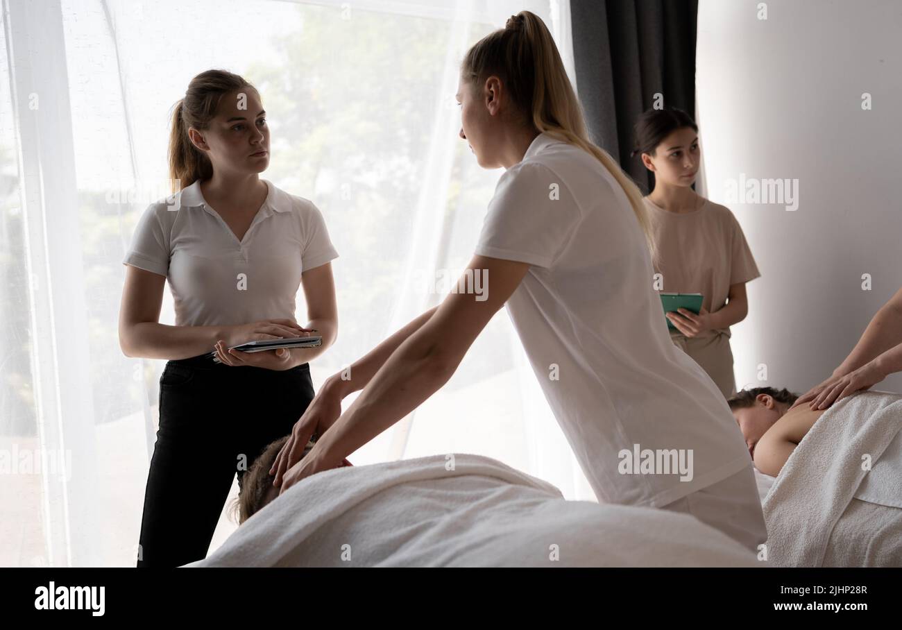 Lehrer, der den Schülern hilft, Masseuse zu werden, Frauen, die eine Rückenmassage für die Patienten machen, Massagetraining Stockfoto
