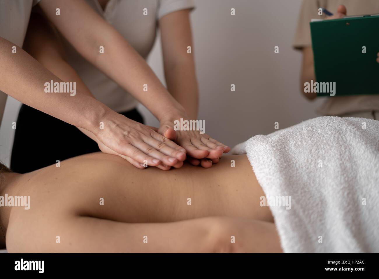 Massageliegen, Ausbildung von Massagetherapeuten, Lehrer hilft Schüler, Wellness-Rückenmassage zu tun Stockfoto