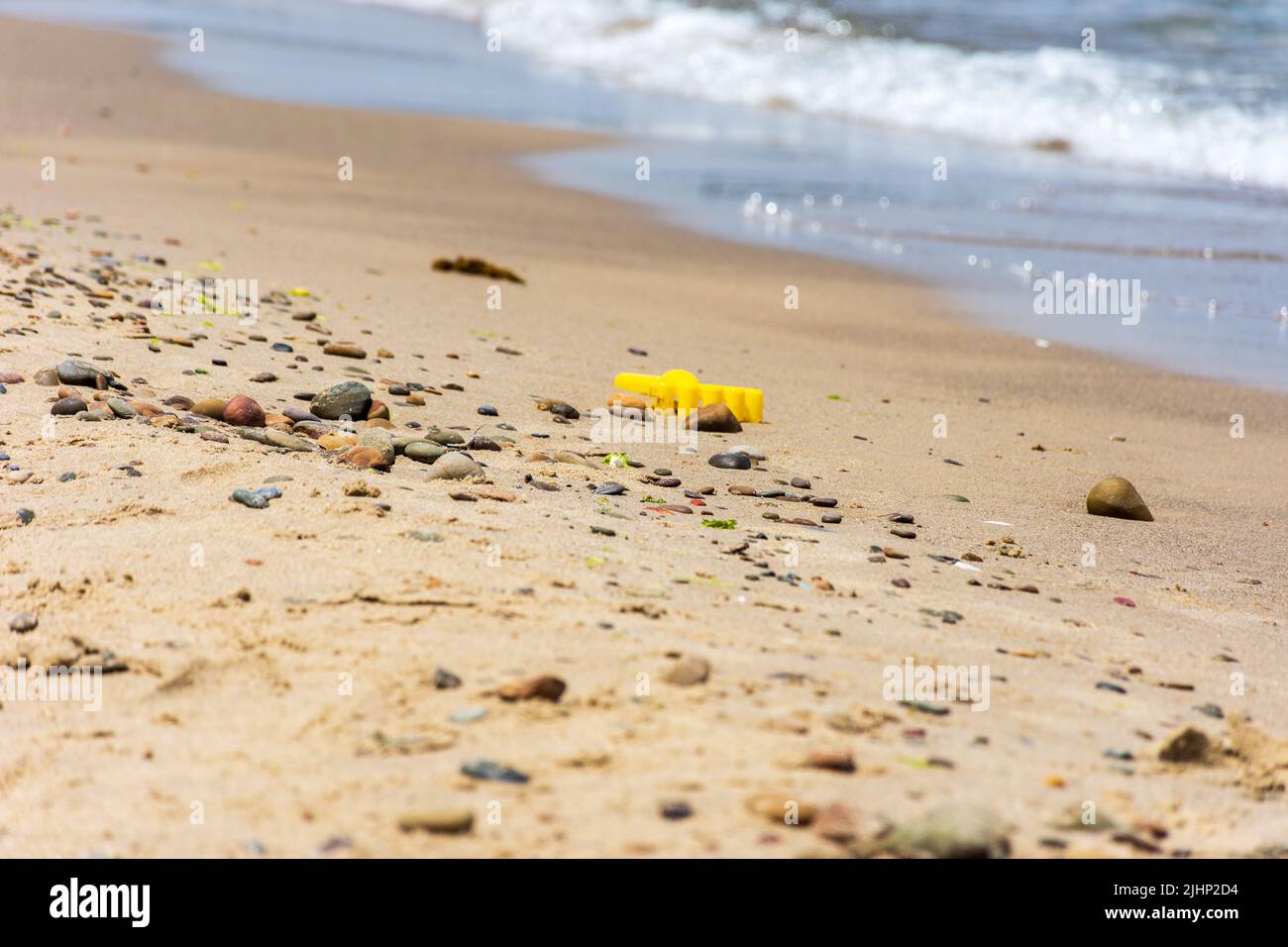 Nahaufnahme der Plastikschaufel eines gelben Kindes am Strand. Stockfoto