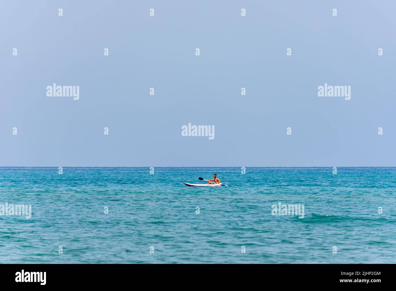 Ein junger Mann, der im Mittelmeer mit dem Kajak unterwegs ist. Kajaksportkonzept. Stockfoto