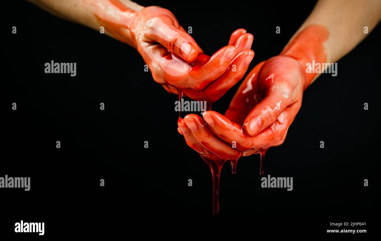 Frauenhände in einer zähflüssigen roten Flüssigkeit ähnlich dem Blut. Stockfoto