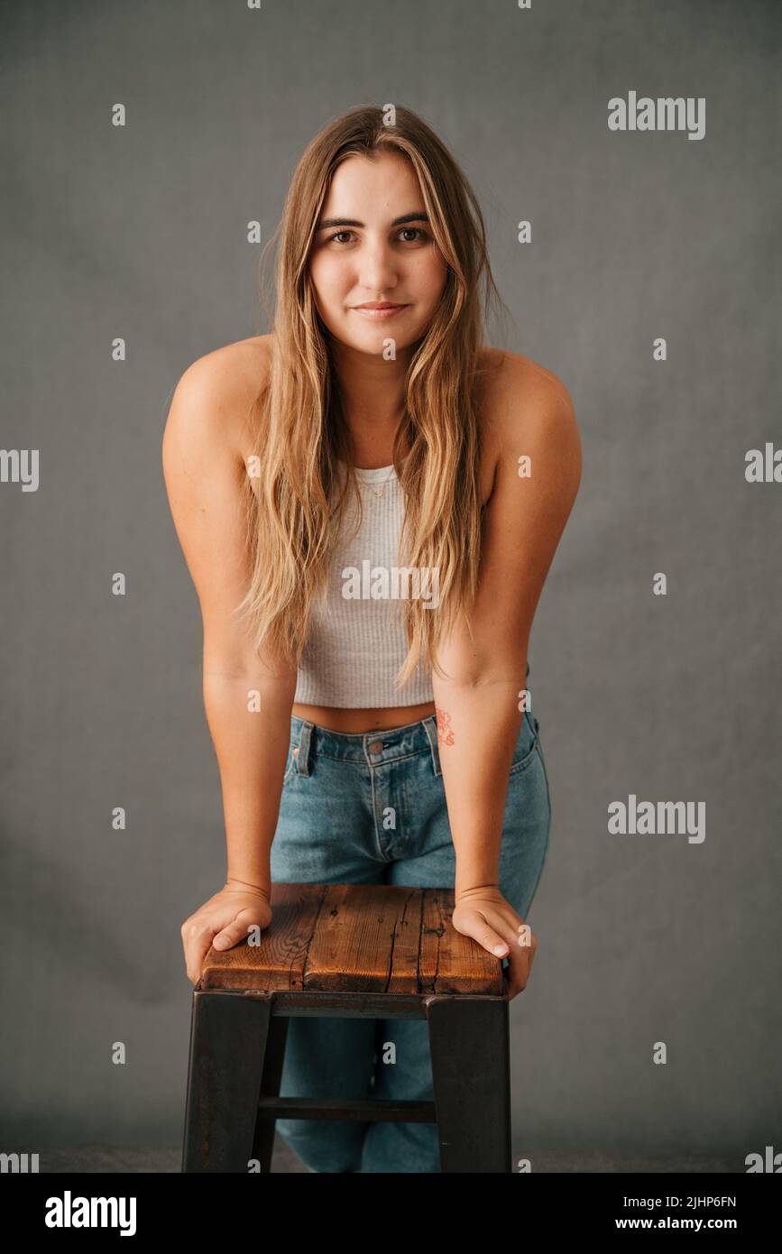 Nahaufnahme der jungen Frau, die sich mit ihren Händen auf einen Stuhl lehnt Stockfoto