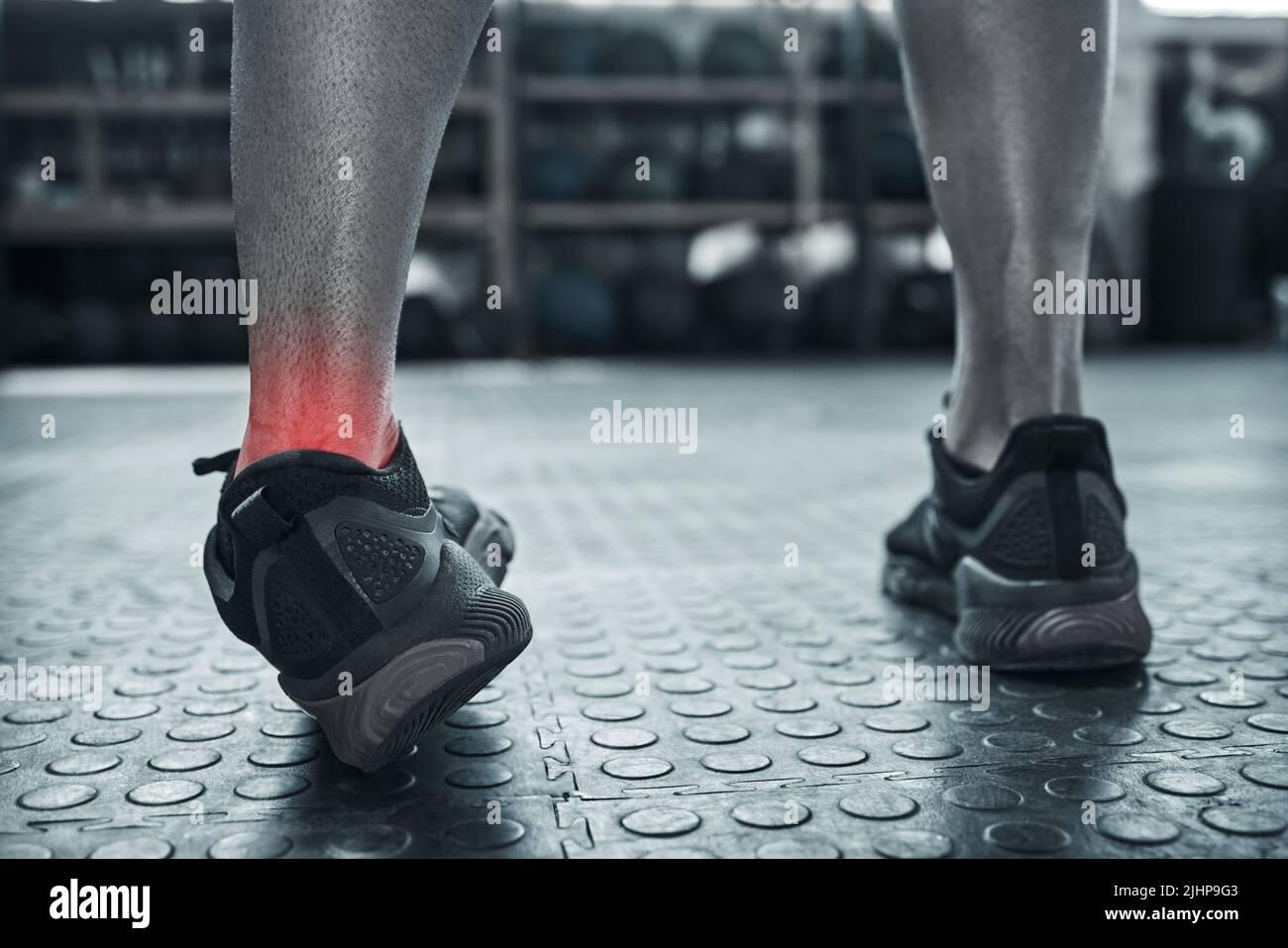 Eine Knöchelverstauchung durch eine falsche Bewegung. Bewegung kann zu Muskelbelastungen führen. Nahaufnahme bei Fußschmerzen eines Bodybuilders im Fitnessstudio. Rote CGI-Punkte markieren Stockfoto