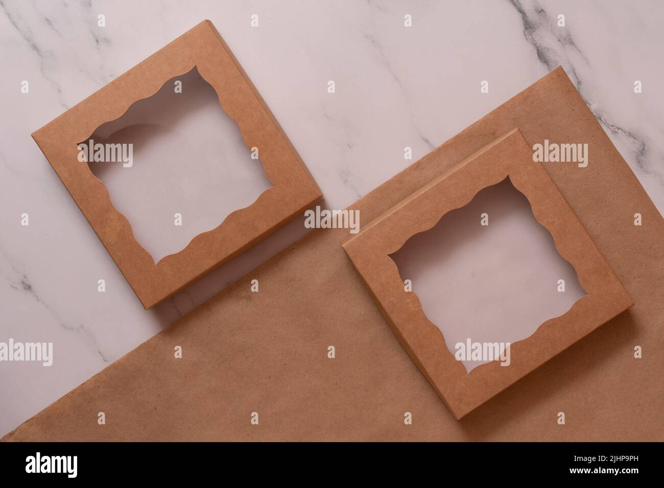 Zwei Schachteln mit transparentem Deckel auf Bastelpapier mit Muschelschalen und Geißelservietten. Stockfoto