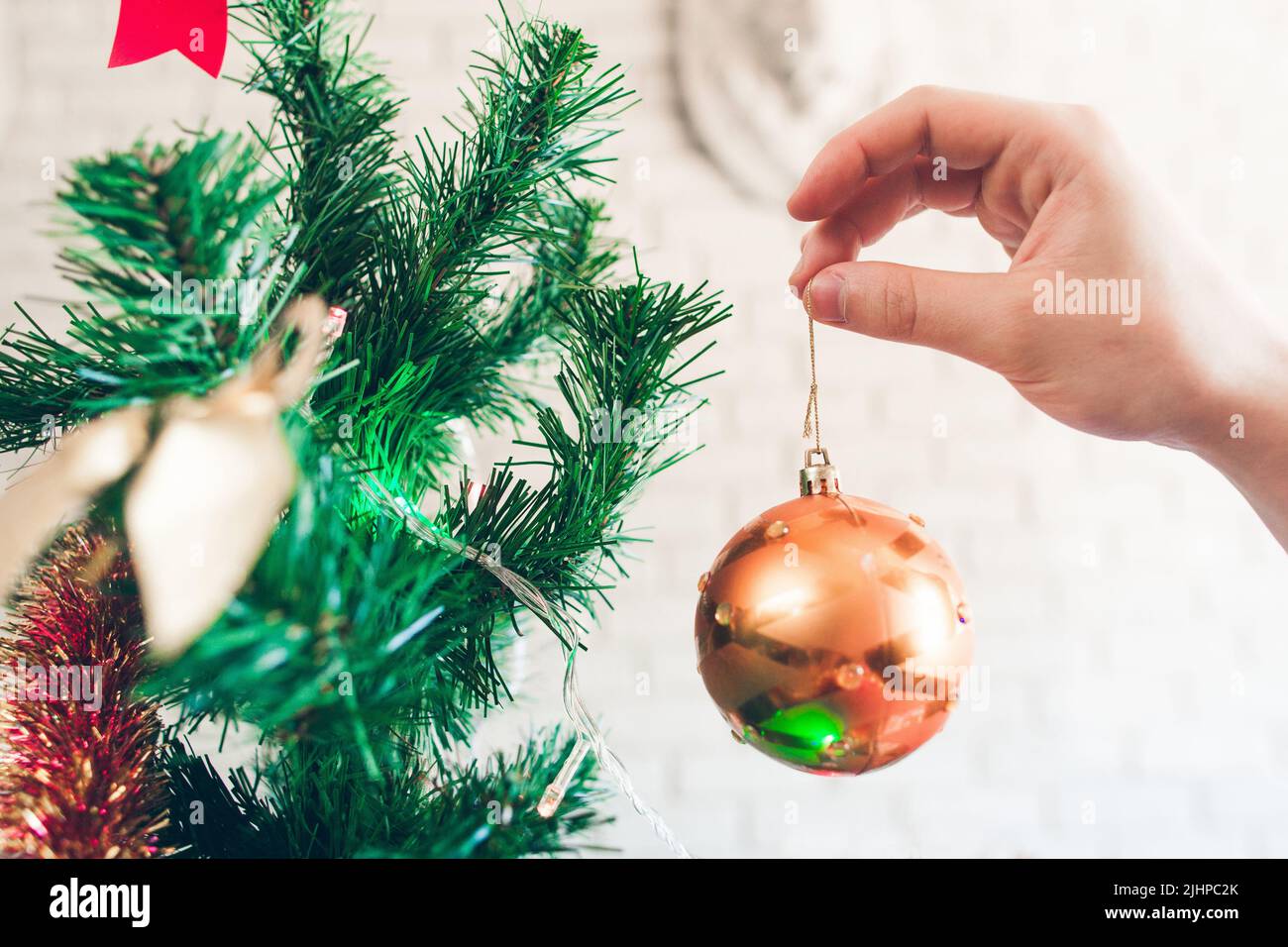 Nahaufnahme der Hand mit goldener Deko-Kugel Stockfoto