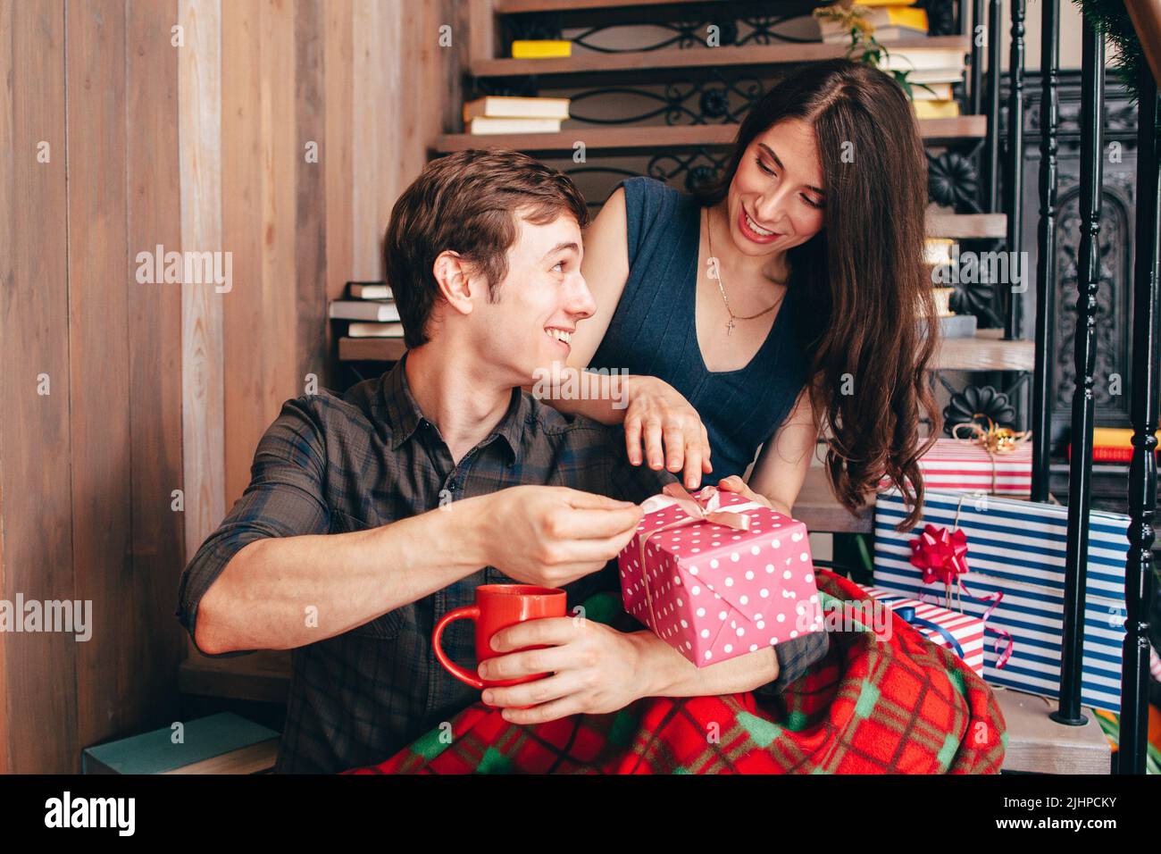 Lächelnder Mann, der der Frau ein Weihnachtsgeschenk übergibt Stockfoto