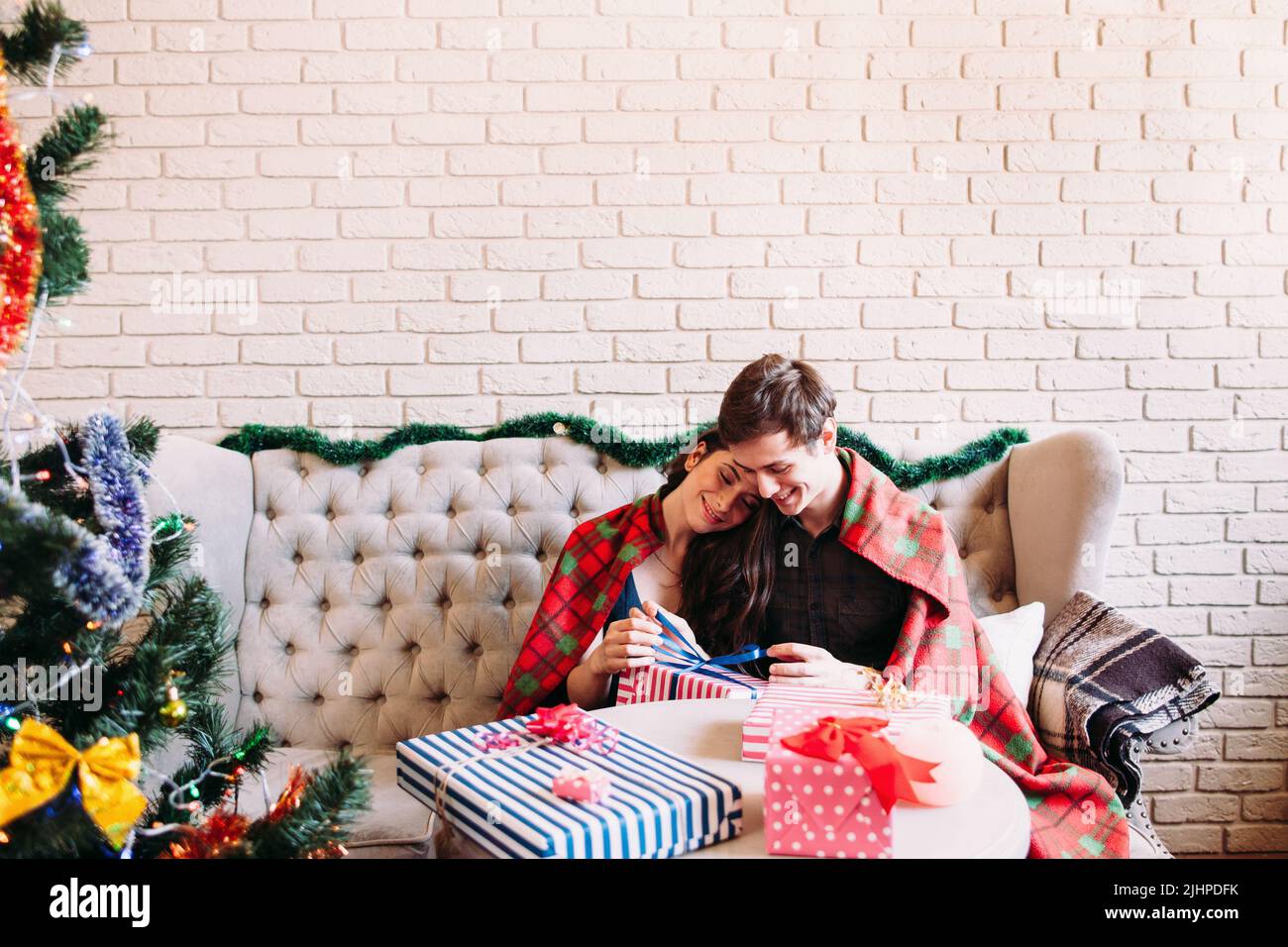 Glückliches Paar, das in der Nähe des Weihnachtsbaums sitzt Stockfoto