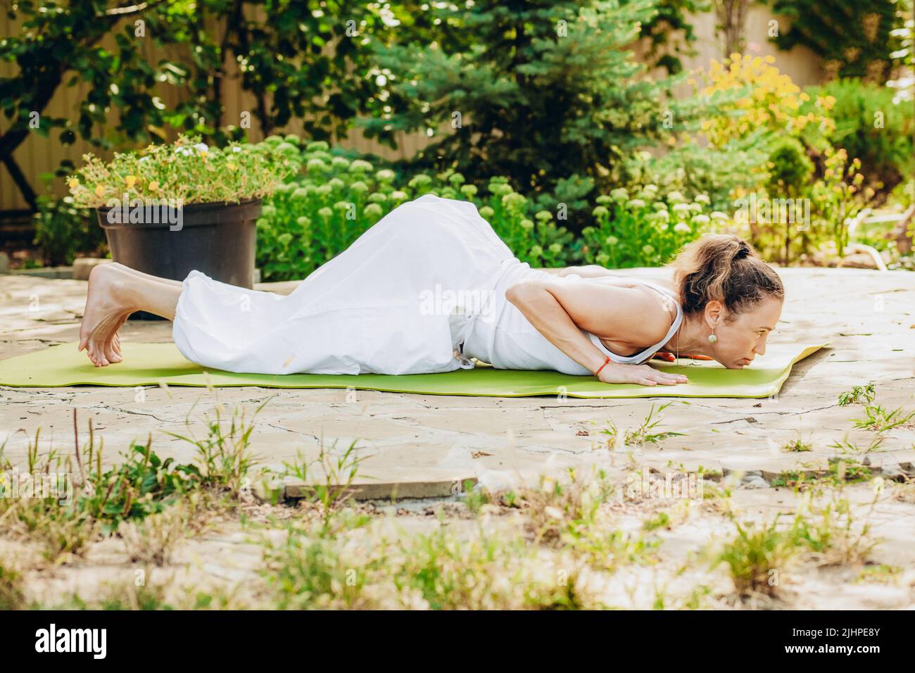 Junge Frau praktiziert Yoga im Garten. Surya namaskar, vierPunktPose