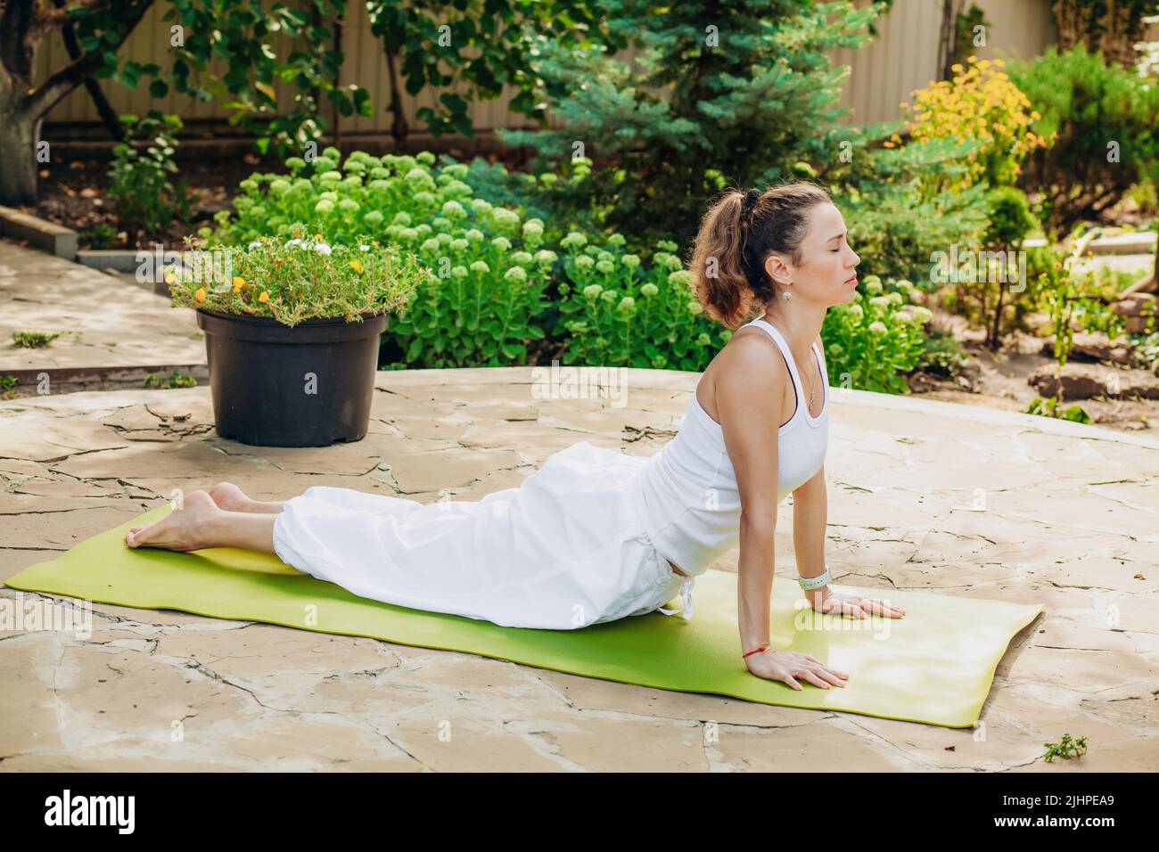 Junge Frau praktiziert Yoga im Garten. Surya namaskar, Bhujangasana