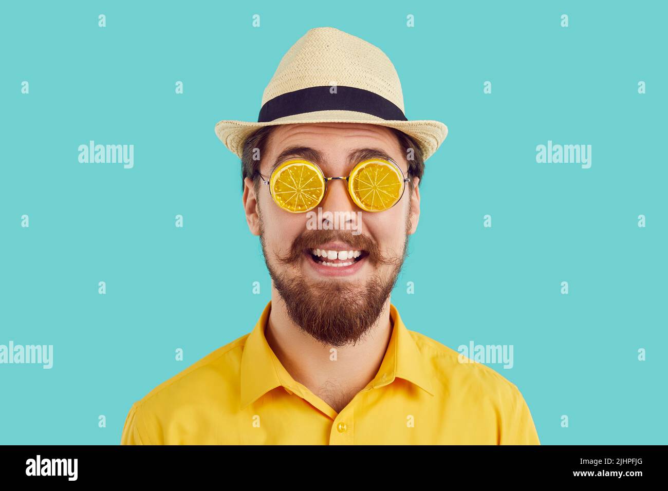 Studio-Porträt eines glücklichen Mannes im Sommerhut und lustige Sonnenbrille als orangefarbene Scheiben entworfen Stockfoto