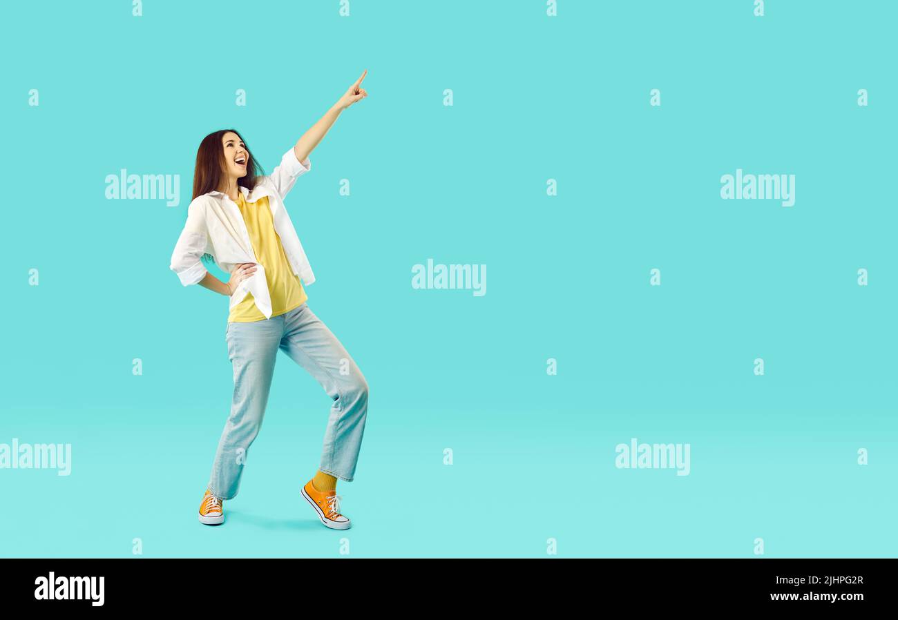 Fröhliche lustige junge Frau in guter Laune, die Spaß hat und auf hellblauem Hintergrund isoliert tanzt. Stockfoto