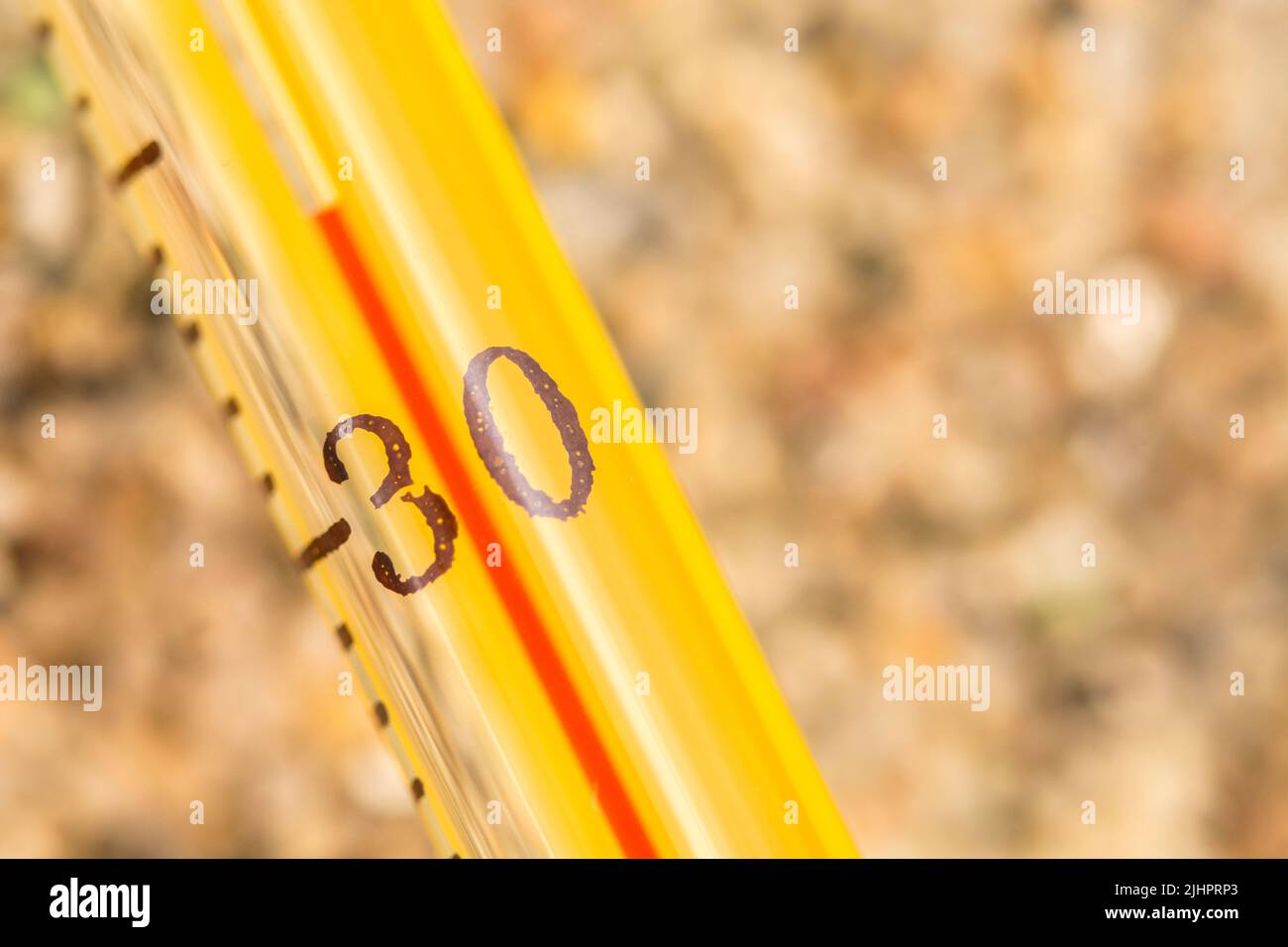 Nahaufnahme-Alkoholthermometer aus Glas auf grobem Sand, Anzeige 34 C. für 2023 Sommer Hitzewelle, UK Hitzewelle, heißes Wetter, hohe Temperaturen, schwere Hitze Stockfoto