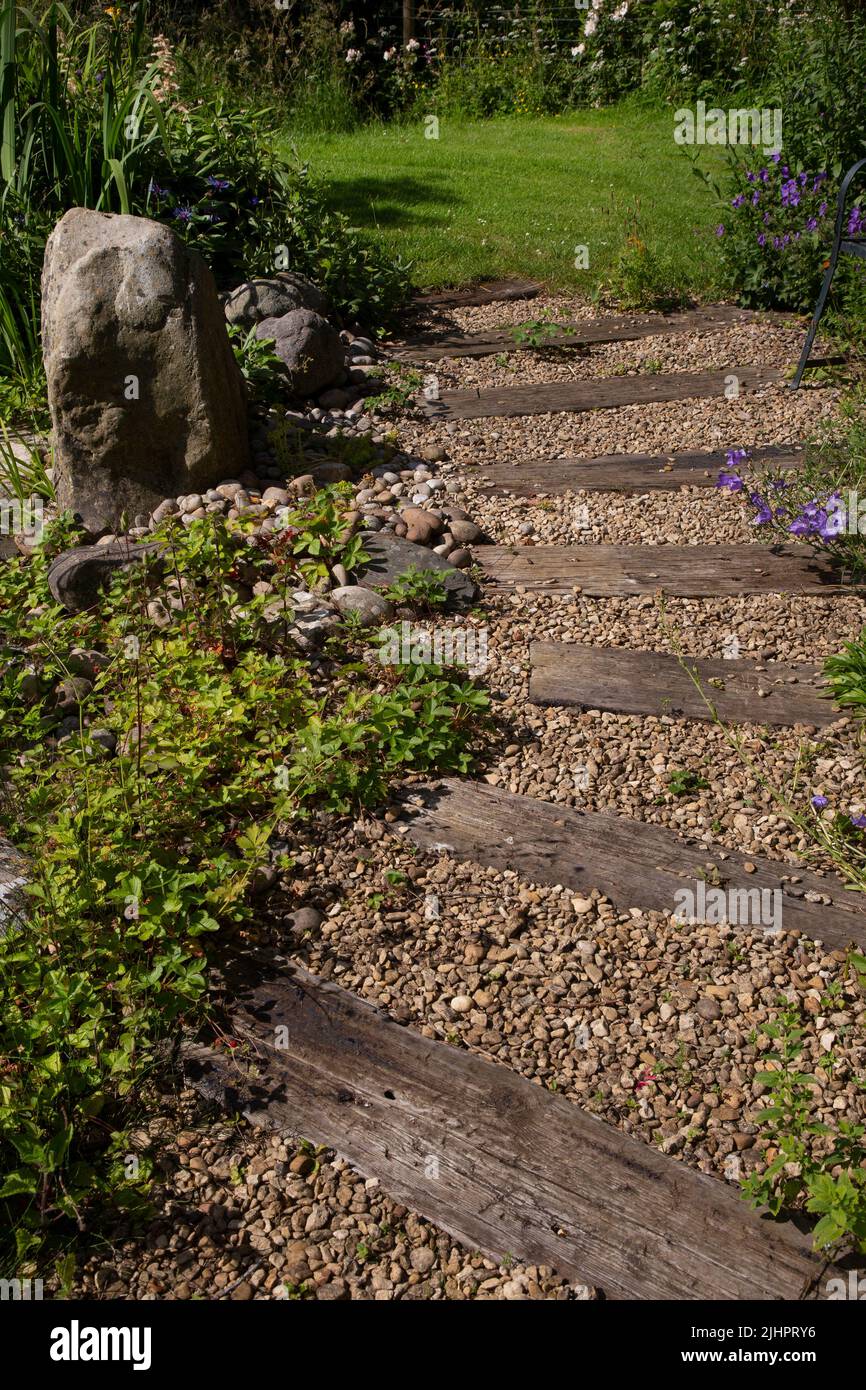 Englischer Gartenweg mit Kies und Holzverschlafern Stockfoto