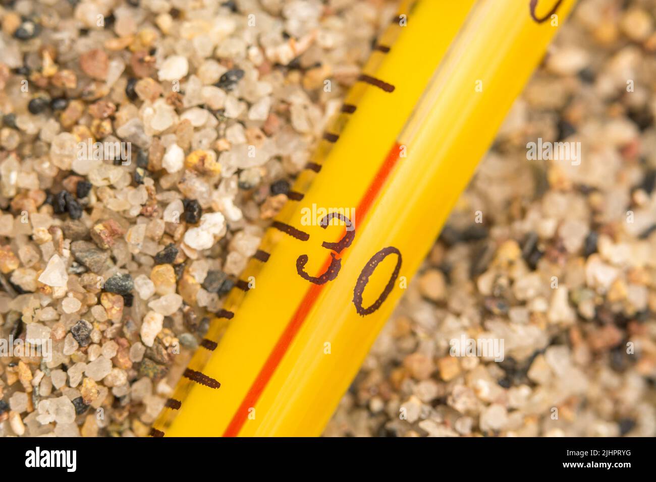 Nahaufnahme-Alkoholthermometer aus Glas auf grobem Sand, Anzeige 33 C. für 2023 Sommer Hitzewelle, UK Hitzewelle, heißes Wetter, hohe Temperaturen, schwere Hitze Stockfoto