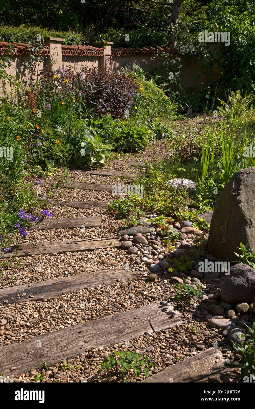 Englischer Gartenweg mit Kies und Holzverschlafern Stockfoto