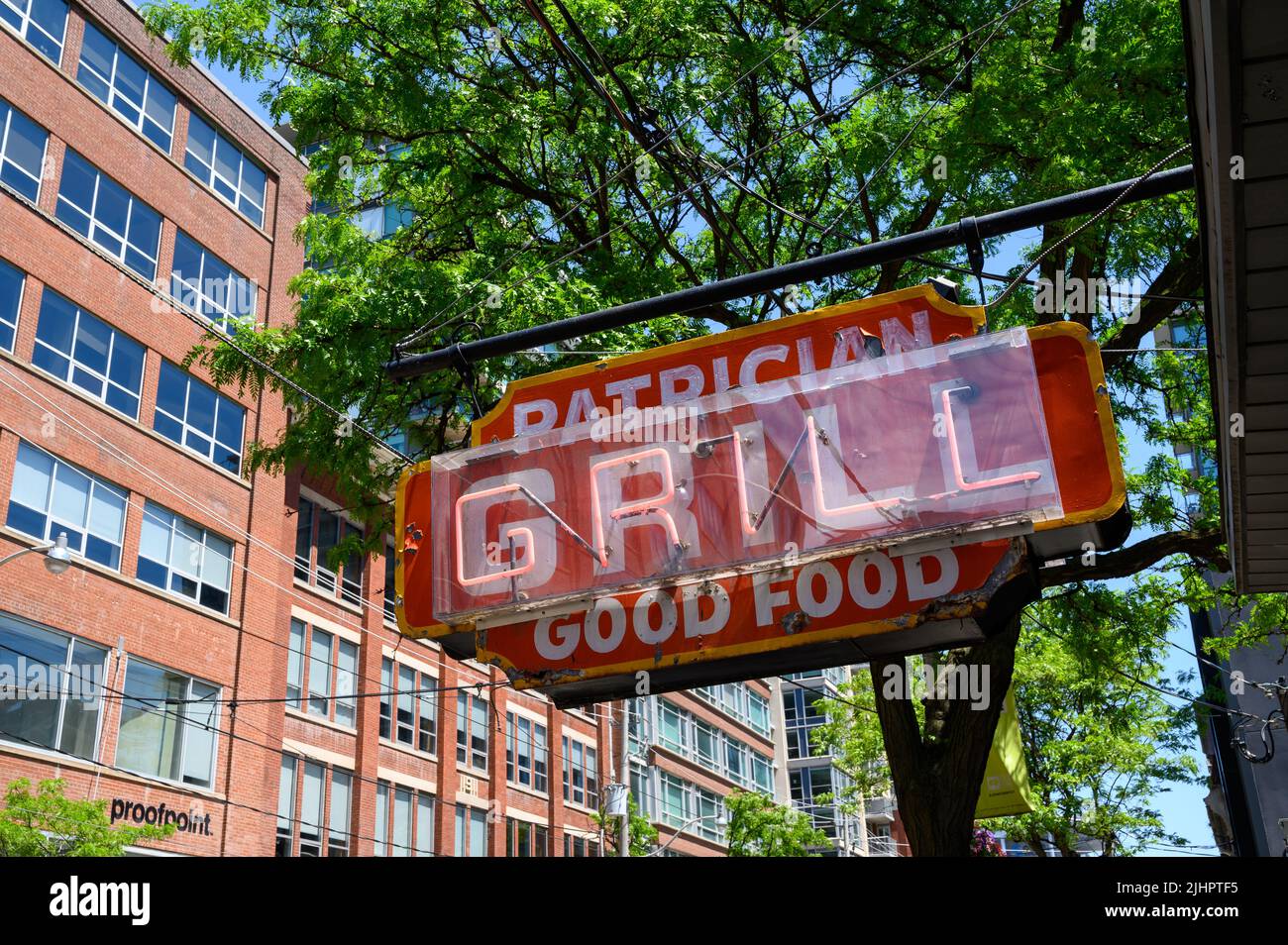Ein abgenutztes und verwittertes, neonfarbenes und handbemaltes Restaurantschild für Patrician Grill, das „Good Food“ in King St East, Toronto, Ontario, Kanada, fördert. Stockfoto