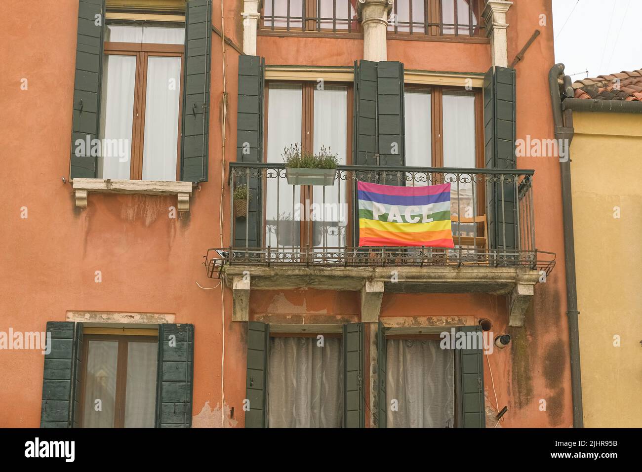 Regenbogen-Friedensflagge an der Fassade des Stadthauses zur Unterstützung des Stoppkrieges in der Ukraine. Stockfoto