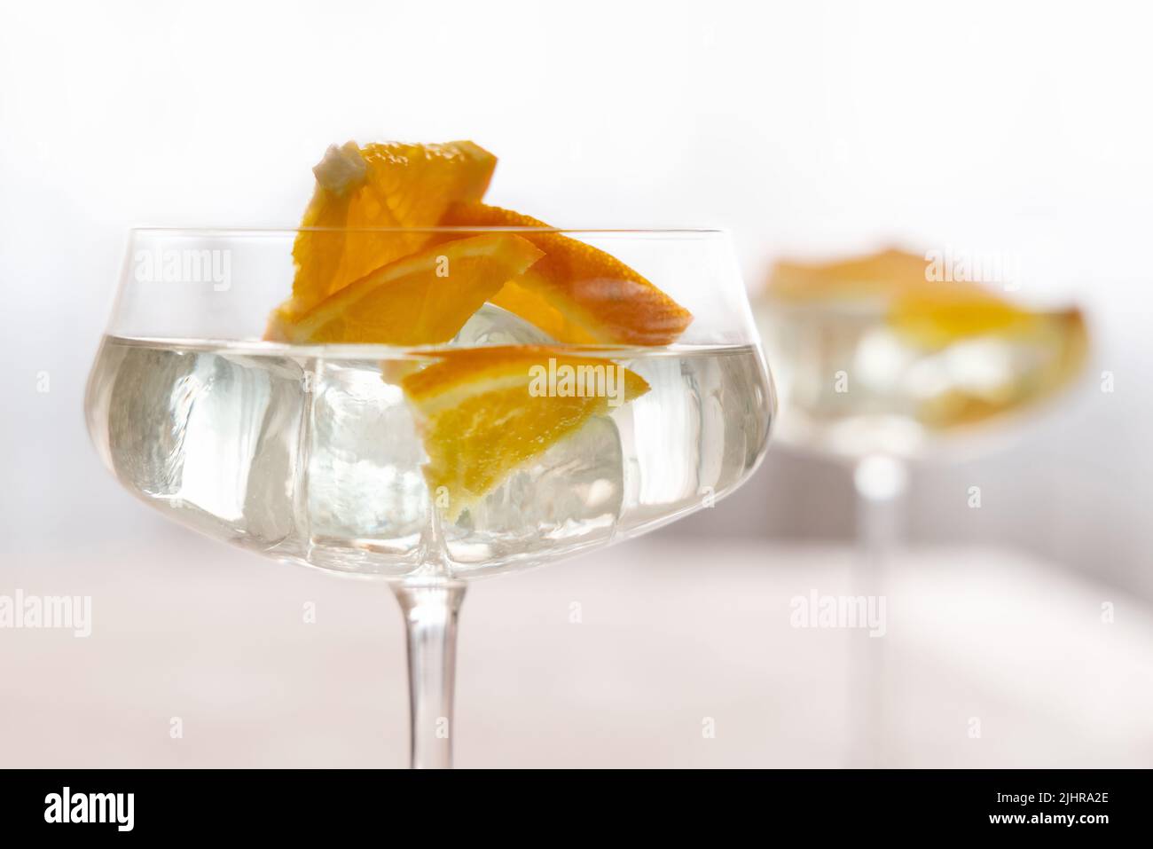 Transparenter Cocktail mit Eiswürfeln in einem Champagner-Coupé-Glas, verziert mit Orangenscheiben aus nächster Nähe. Tropisches Getränk an der Bar. Sommerurlaub Mo Stockfoto
