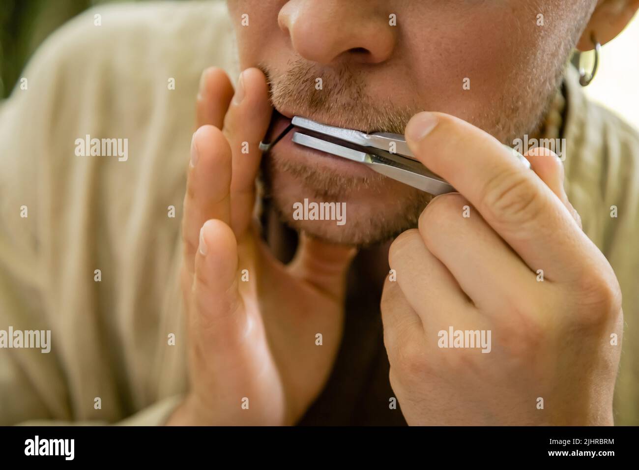 Beschnittene Ansicht des Mannes, der im Freien auf der Maultrommel spielt Stockfoto