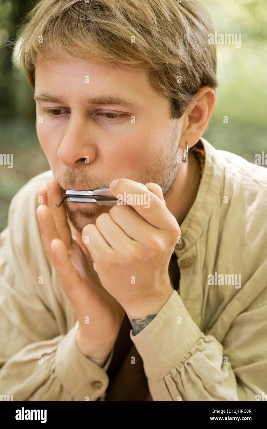 Porträt eines Mannes, der im Wald Maultrommel spielt Stockfoto