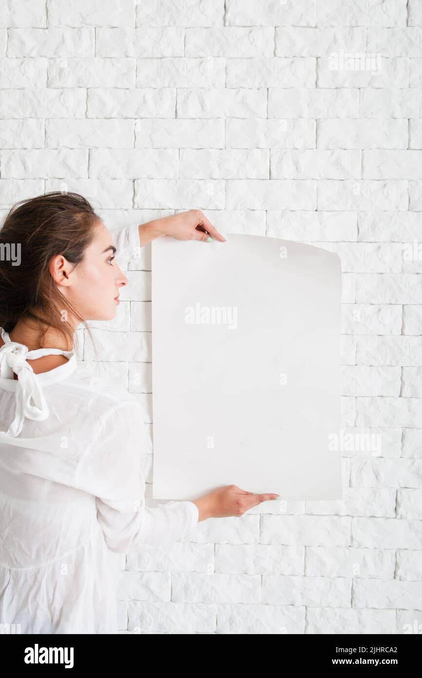 Junge Frau, die auf ein leeres Blatt Papier schaut Stockfoto