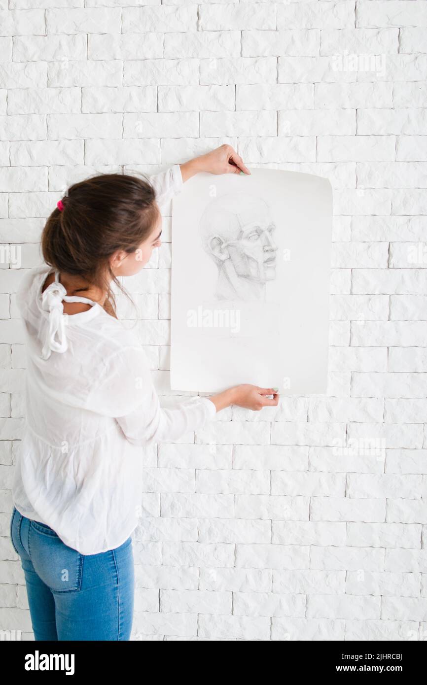 Frau, die auf ein Bleistiftportrait an der Wand schaut Stockfoto