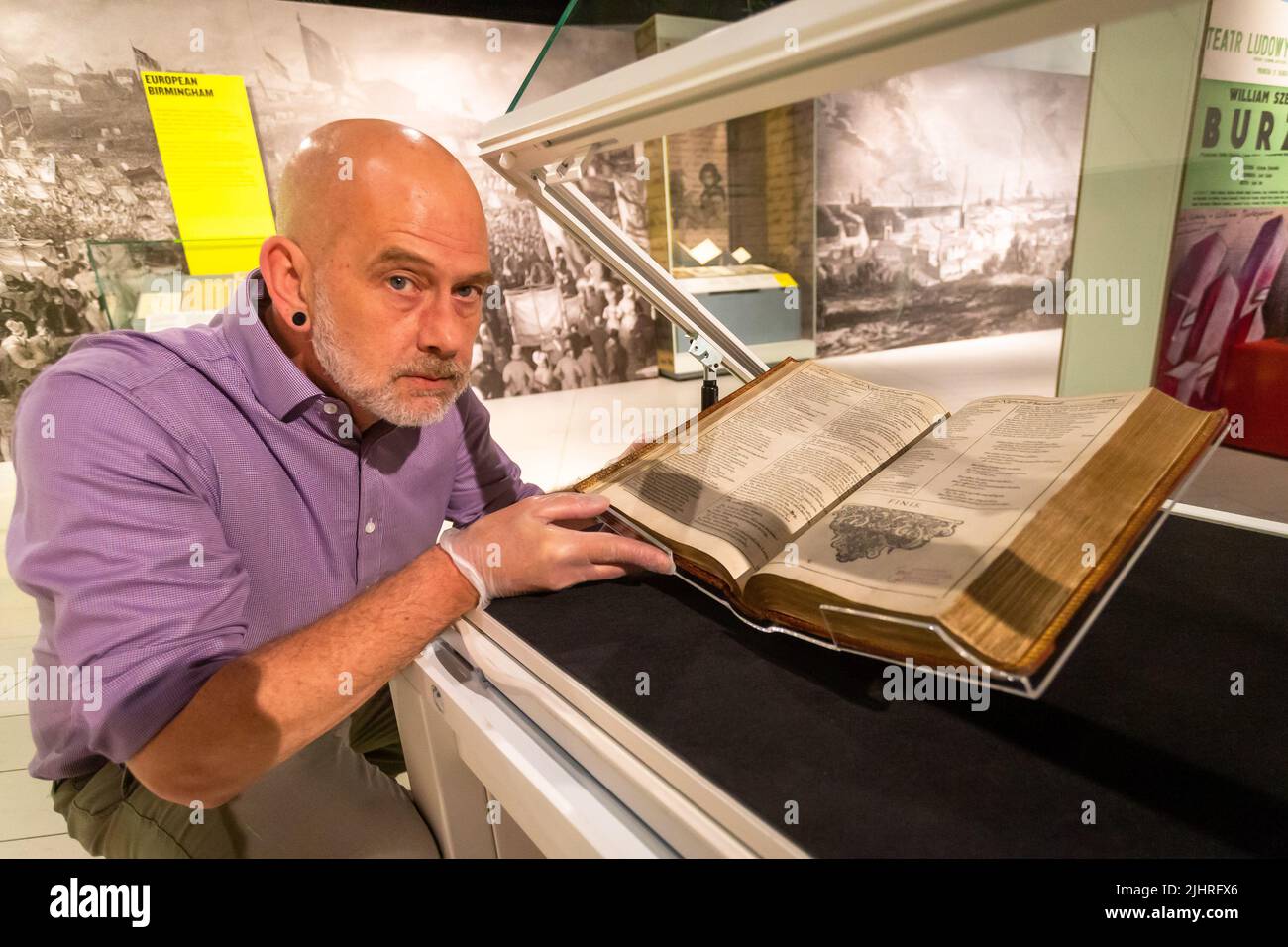 Birmingham, Großbritannien. 20.. Juli 2022. Tom Epps, Cultural Partnership Manager der Library of Birmingham, nimmt eine abschließende Anpassung an das seltene Shakespeare First Folio aus dem Jahr 1623 vor, bevor es zusammen mit vielen anderen bisher unsichtbaren Shakespeare-Artikeln und Büchern in der Library of Birmingham gezeigt wird. Die Ausstellung „alles für alle: Euer Shakespeare, eure Kultur“ läuft vom 22.. Juli bis zum 2022. November. Kredit: Peter Lopeman/Alamy Live Nachrichten Stockfoto