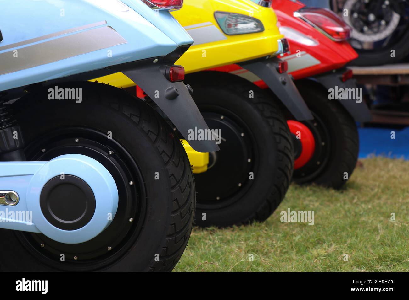 Neue Elektroroller werden auf einem frischen Rasen mit Blick auf den hinteren Teil in Ordnung geparkt. Eco City Transport pendeln Konzept Stockfoto