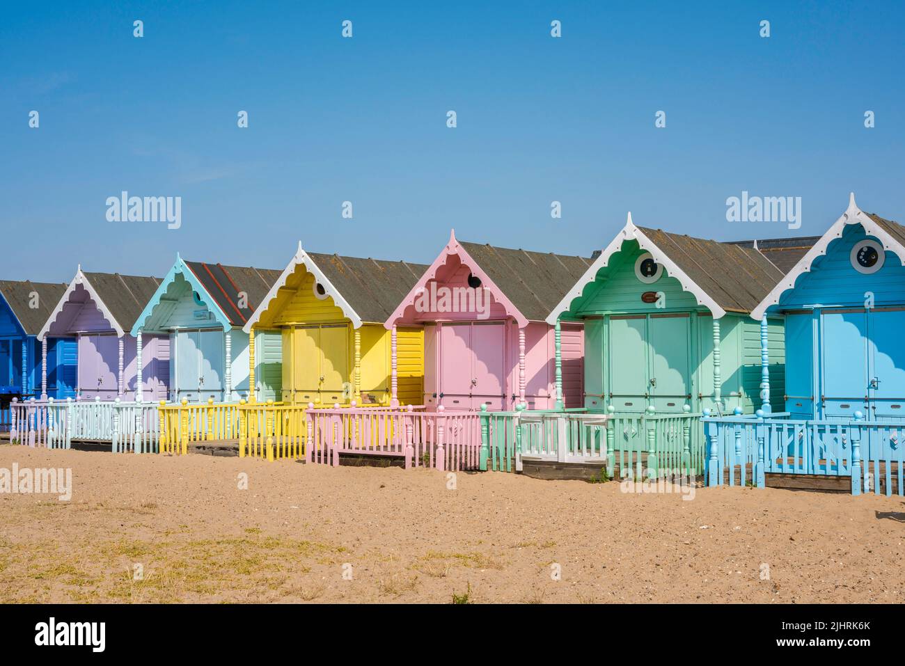 Strandhütten Großbritannien, Blick an einem Sommertag auf eine Reihe farbenfroher traditioneller Strandhütten am Strand in West Mersea, Essex, England, Großbritannien Stockfoto