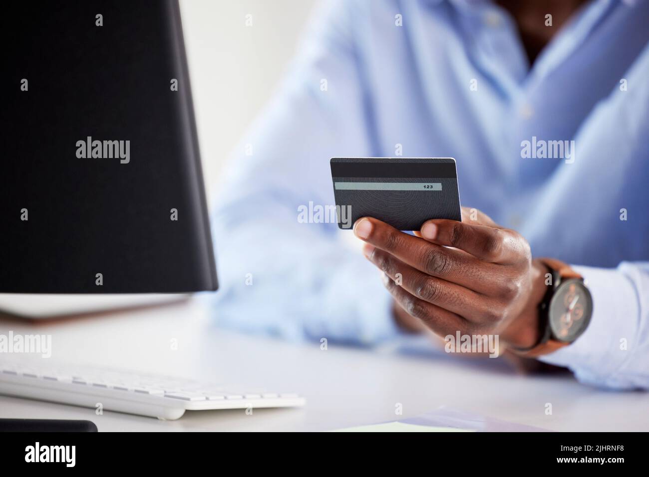Nahaufnahme eines afroamerikanischen Geschäftsmannes, der online mit einer Kreditkarte und einem Computer in einem Büro Geld ausgibt. Kauftransaktion mit Stockfoto