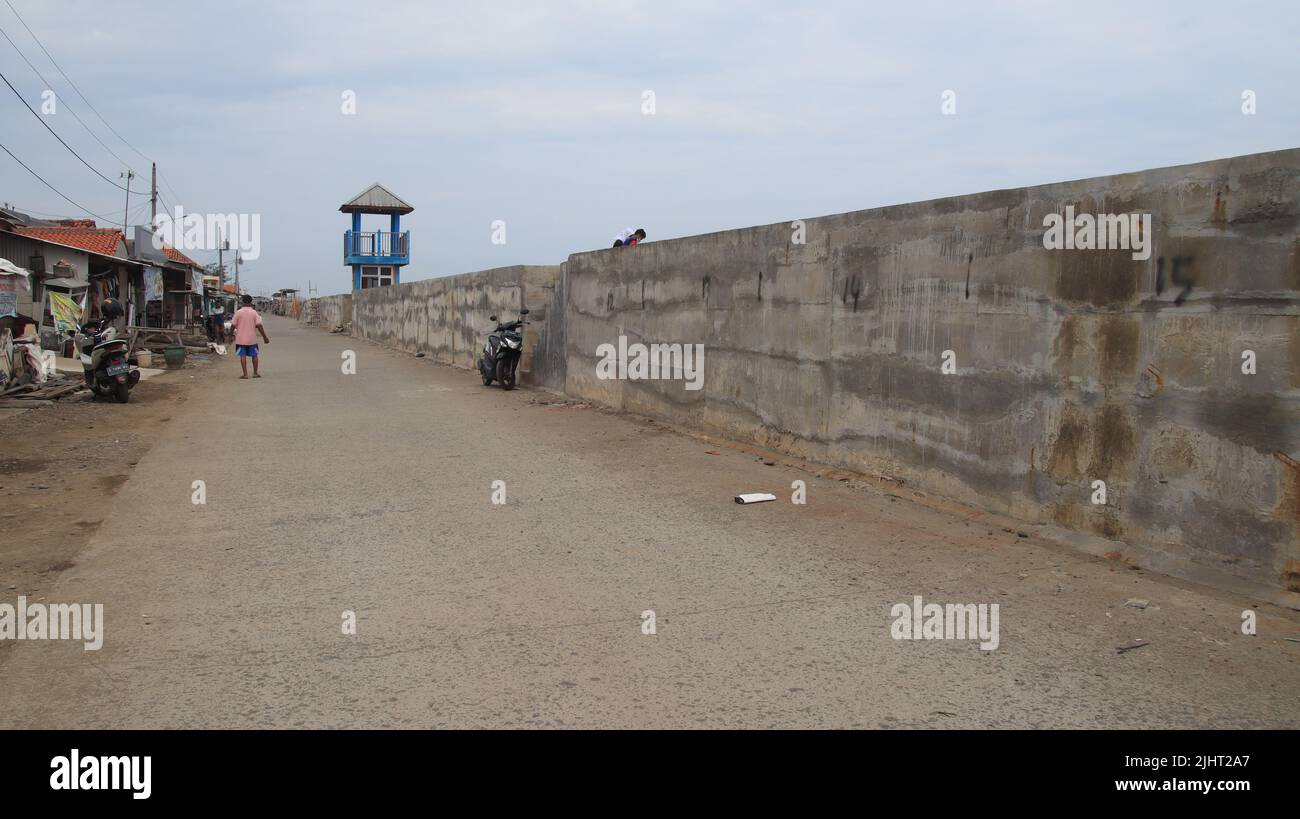 Ein Gebäude, das Meerwasser hält, ein Küstendamm, der Gezeitenwellen mit einem Gehweg hält Stockfoto