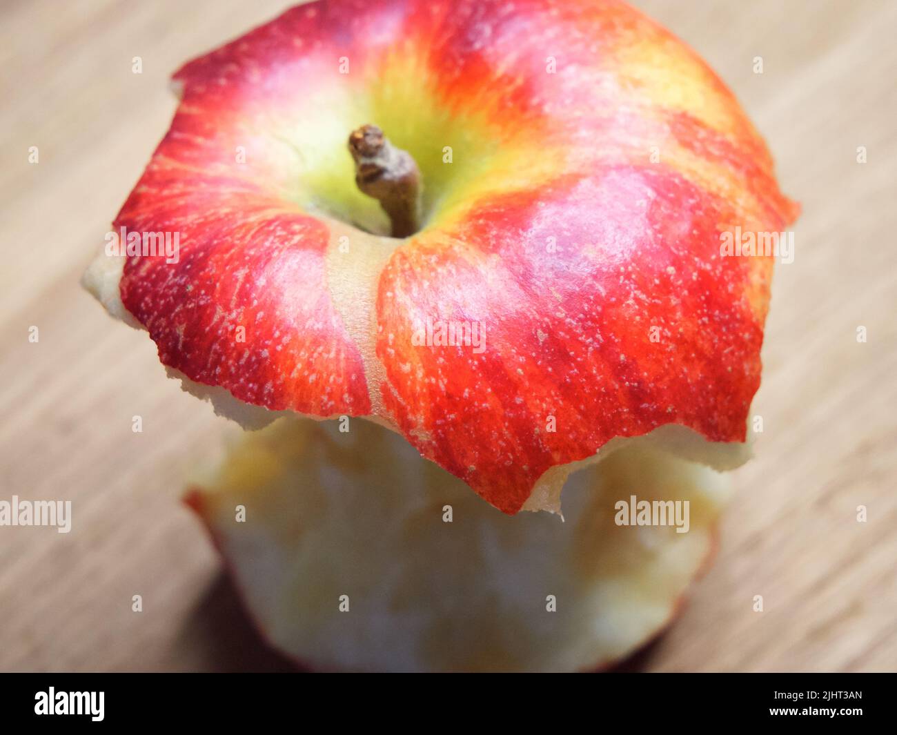 Roter Apfelkern auf einem Holzhintergrund. Ein gebissene Apfel aus der Nähe. Stockfoto