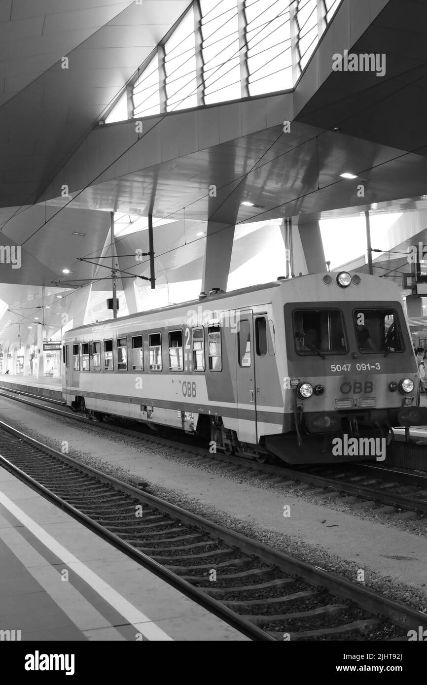 Eine vertikale Graustufenaufnahme des Wiener Hauptbahnhofs mit einem Regionalzug Stockfoto