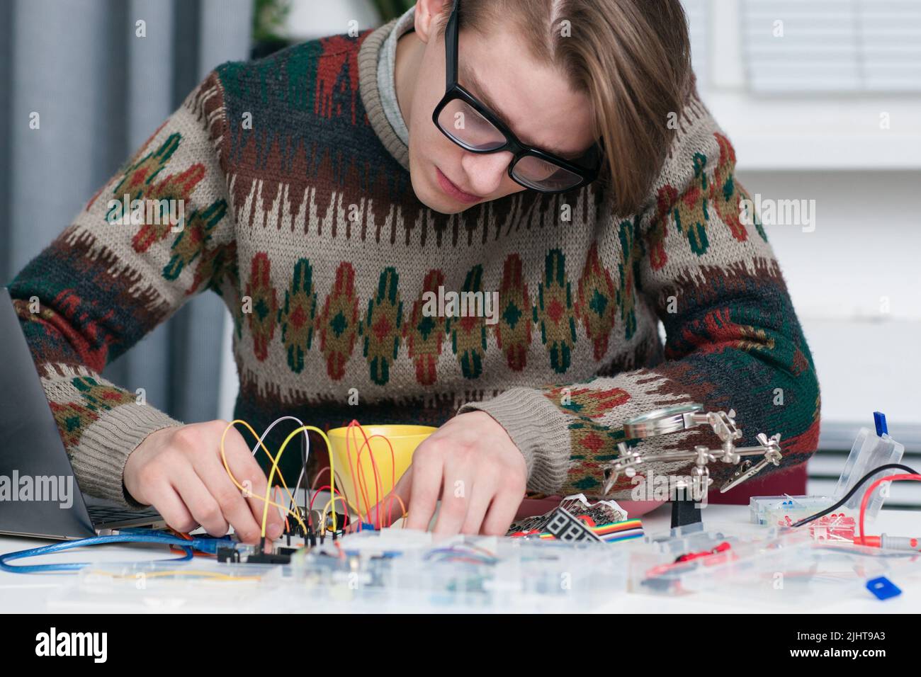 Junger Mann, der intensiv mit elektronischen Teilen arbeitet Stockfoto