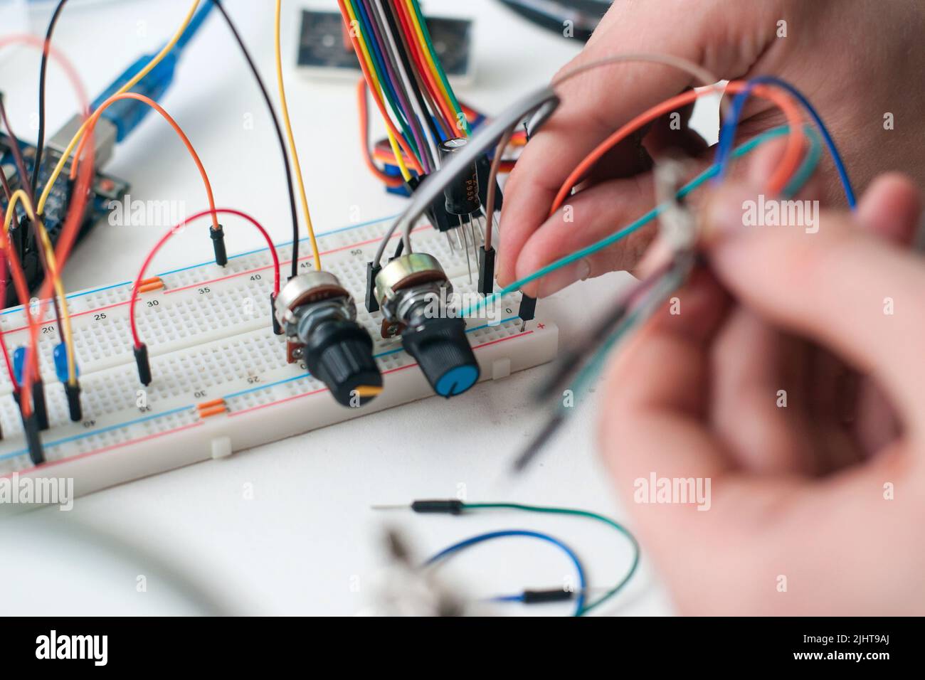 Schließen Sie die Kabel mit den Händen an die Breadboard-Platine an Stockfoto