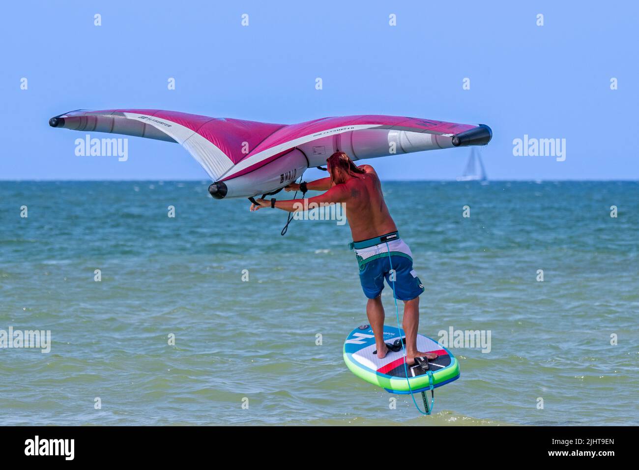 Wing Foiling / Wing Surfing an der Nordsee zeigt Wingboarder / Wing Boarder stehen auf Foilboard / Tragflügelbrett und halten einen aufblasbaren Flügel Stockfoto