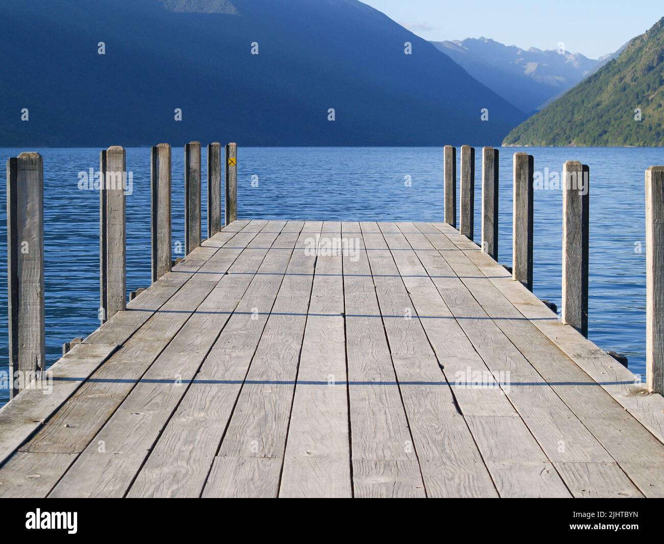 Steg am Roto-iti-See, der in den See mit Berghintergrund projiziert wird, Tasman Lakes District, Neuseeland. Stockfoto