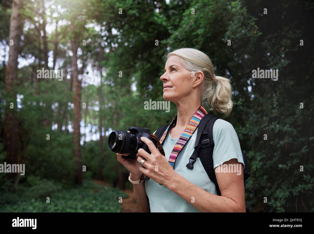 Eine reife kaukasische Frau, die beim Wandern mit ihrer Kamera fotografiert. Ältere Frau, die ihre drahtlose Digitalkamera verwendet, um Fotos in der Natur zu machen Stockfoto