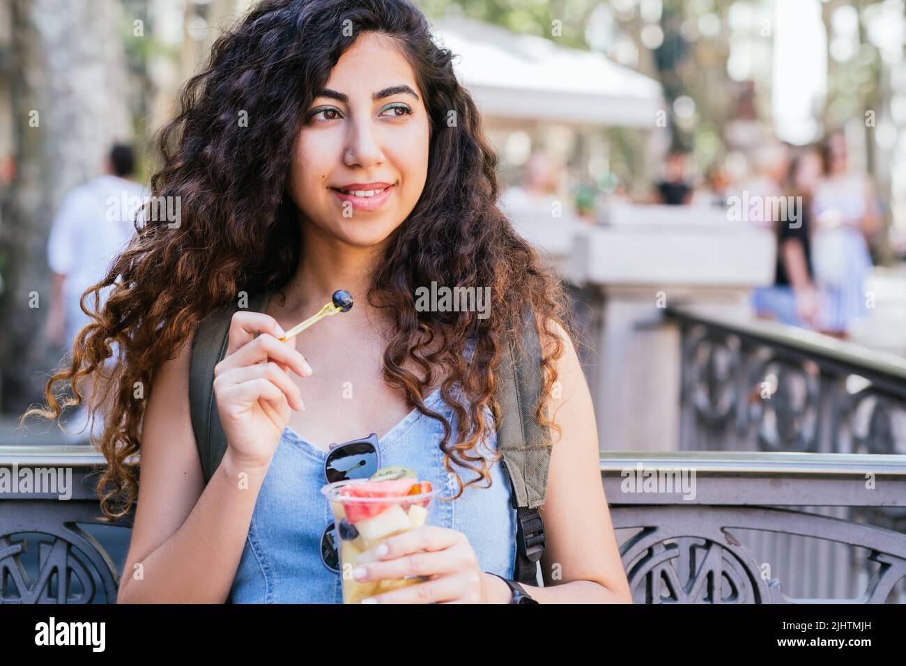 Junger türkischer Reisender mit Rucksack, der eine Tasse frisches Obst in der Straße in der Nähe des unterirdischen Eingangs hält Stockfoto