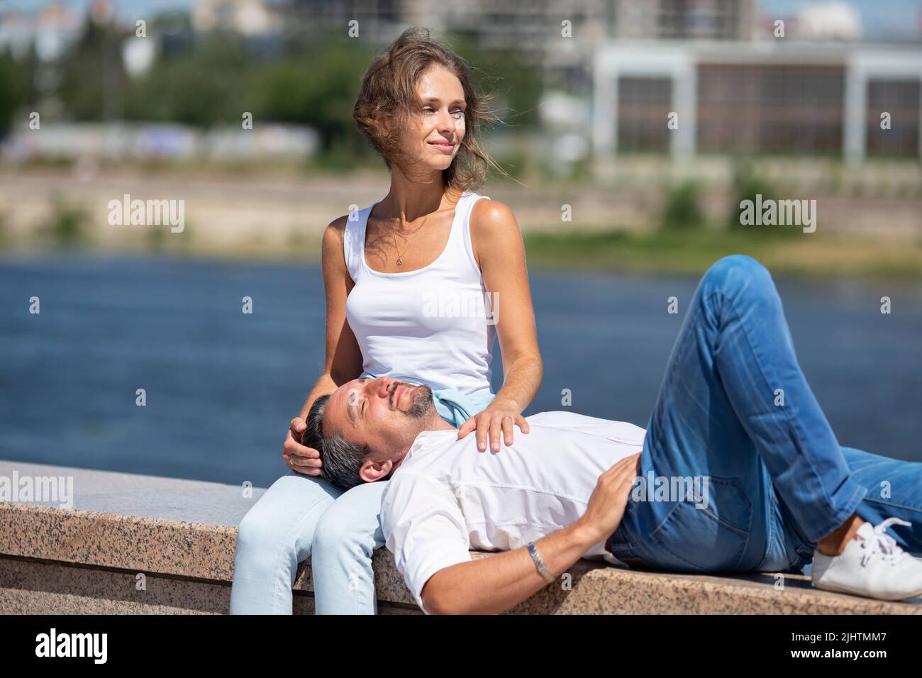 Liebe und Beziehungen - ein Mann liegt auf den Hüften einer Frau, während sie sich beim Gehen im Freien ausruhen. Romantischer Moment zwischen zwei Liebenden. Stockfoto